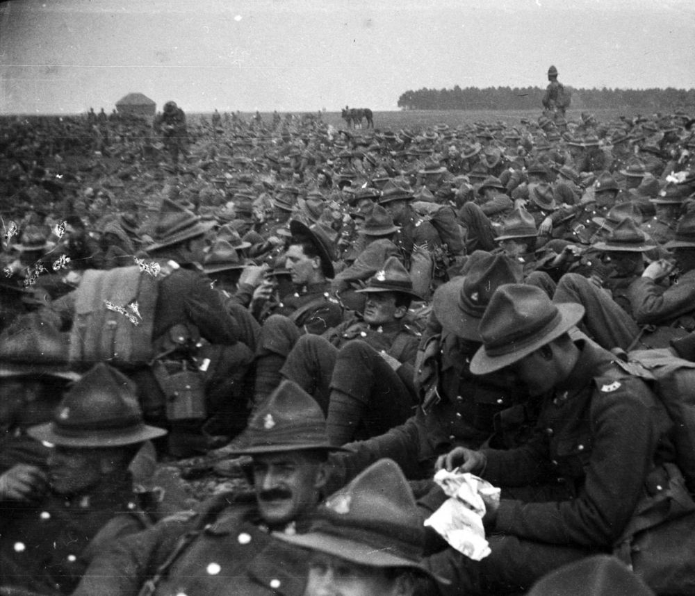 A large group of New Zealand soldiers waiting in a field in full uniform, with webbing, near Sling Camp, England.